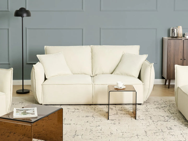 Beige sofa in a living room with a gray wall and wooden floor.
