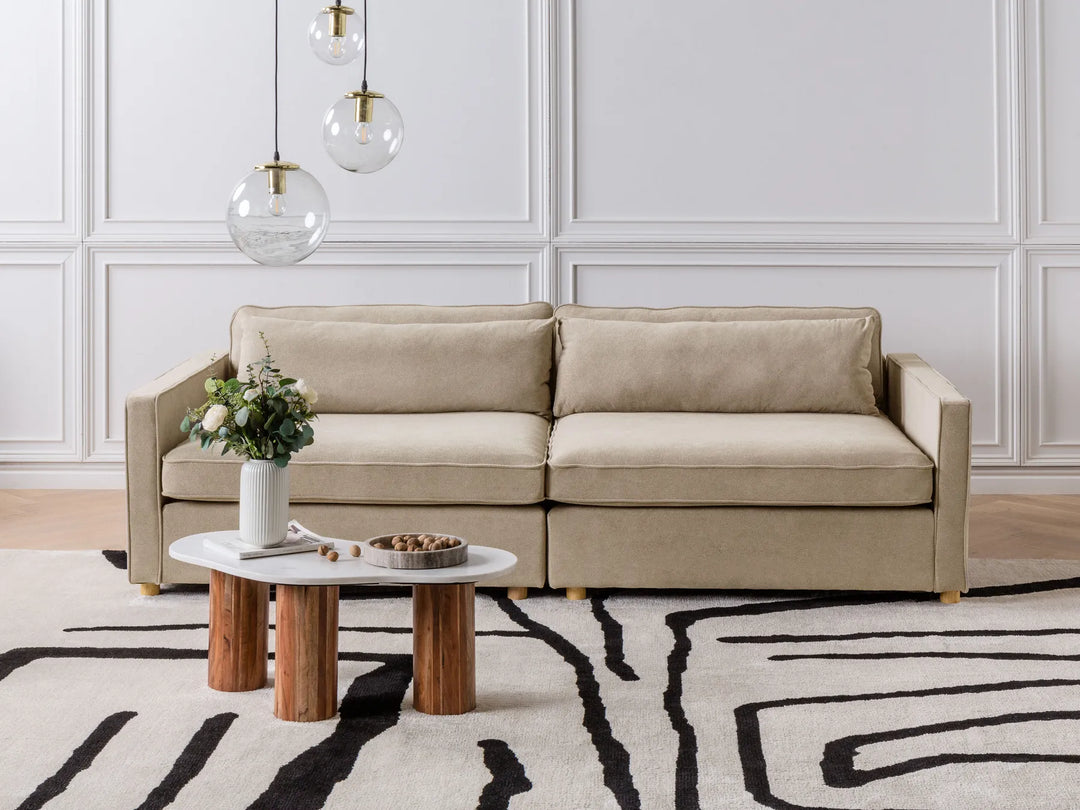 Beige sectional sofa in a living room with a coffee table and decorative items.
