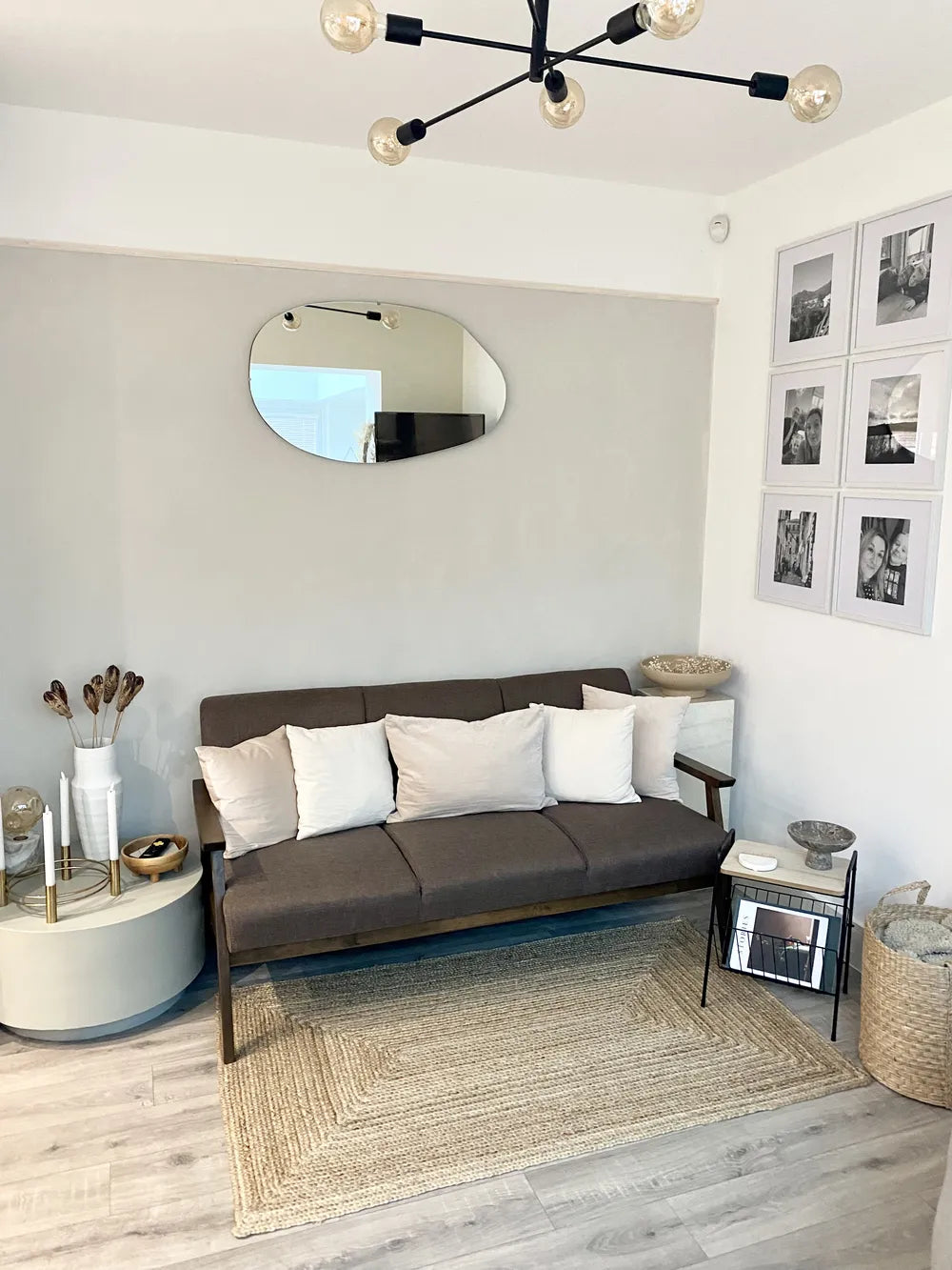 Modern living room with a gray sofa, round mirror, and decorative items.