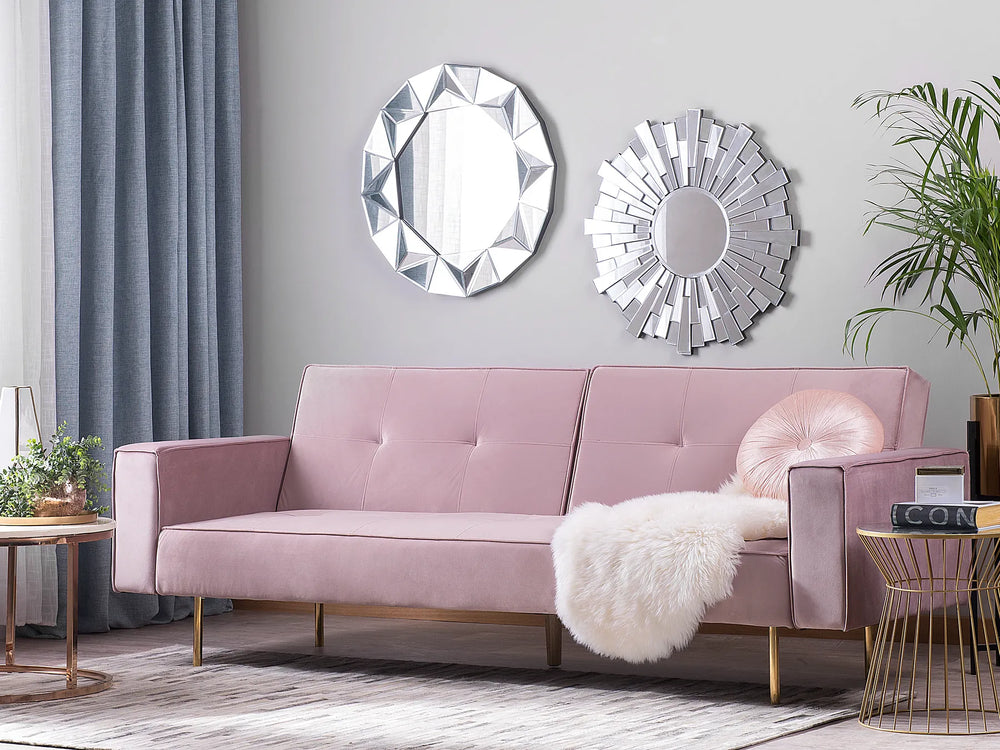 Pink sofa in a living room with decorative mirrors and plants.