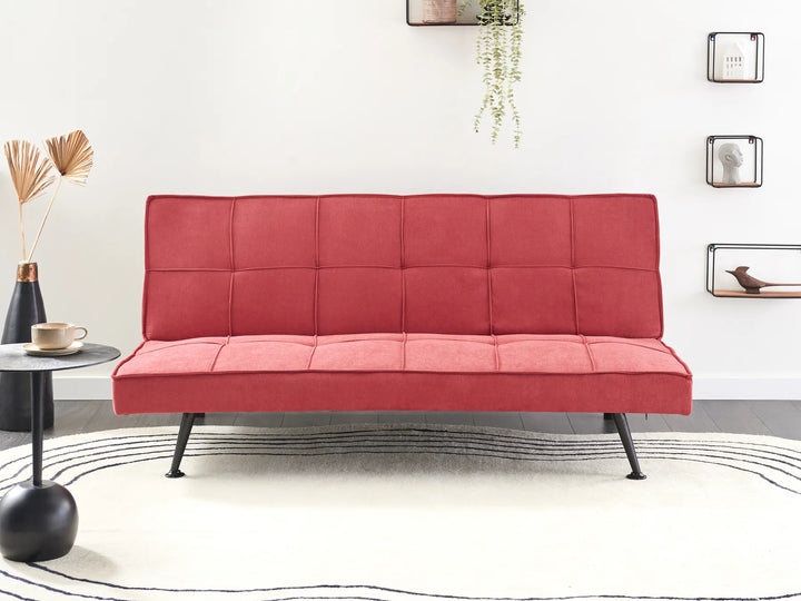 Red futon sofa in a room with decor elements.