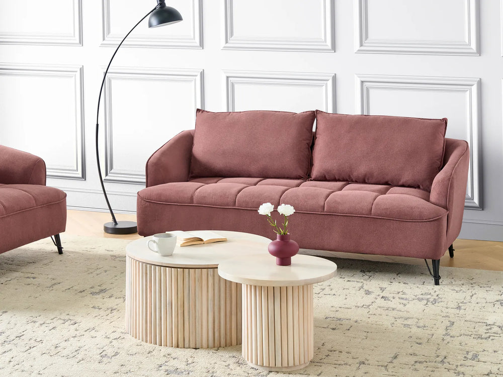 Living room with a mauve sofa, coffee table, and decorative elements.