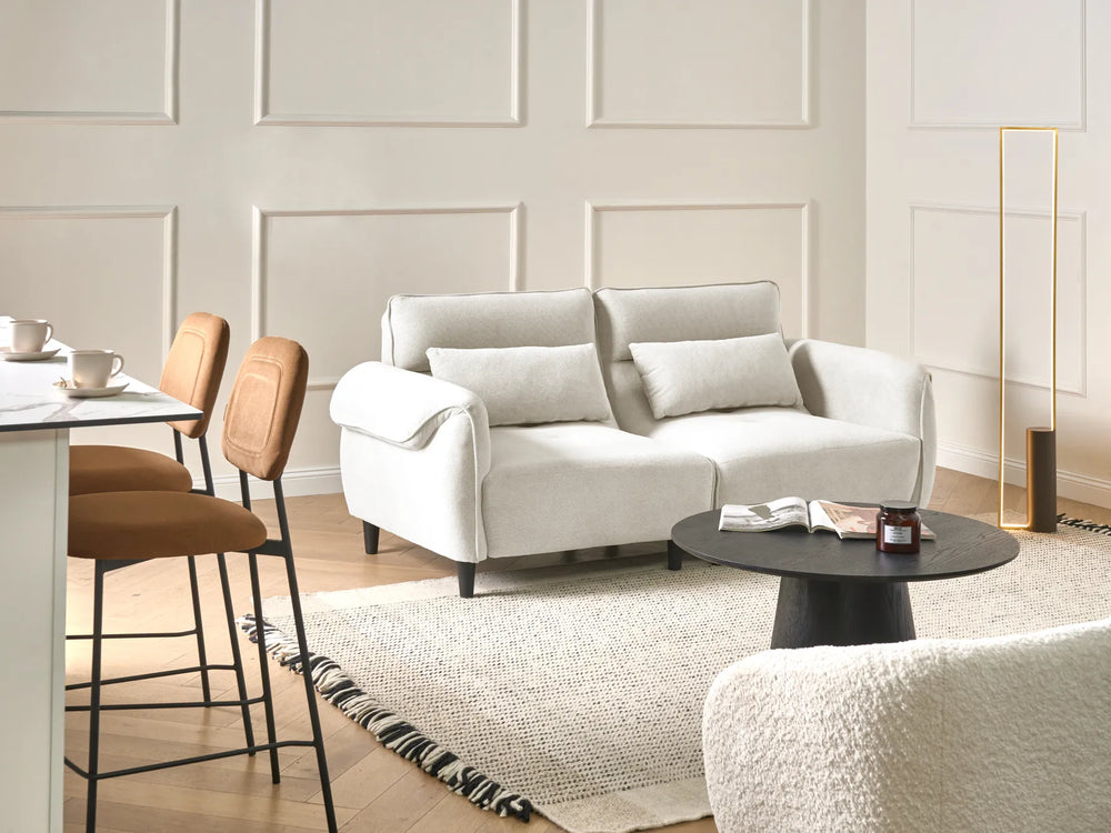 Modern living room with a white sofa, coffee table, and bar stools.