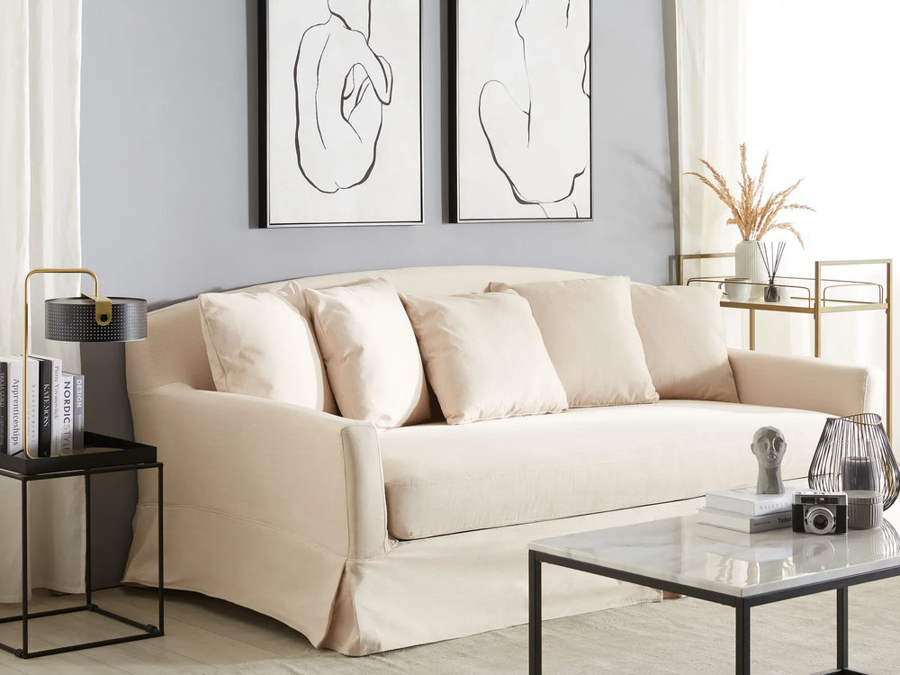 Beige sofa in a living room with abstract art on the wall and decorative items on tables.