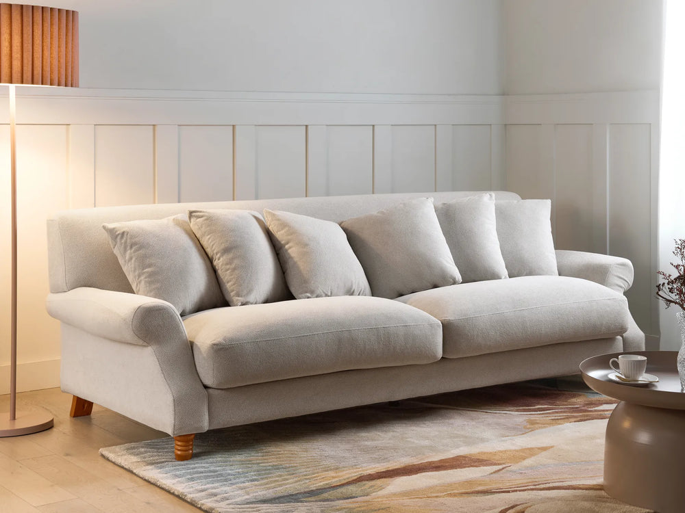 Beige sofa in a living room setting with a lamp and coffee table.