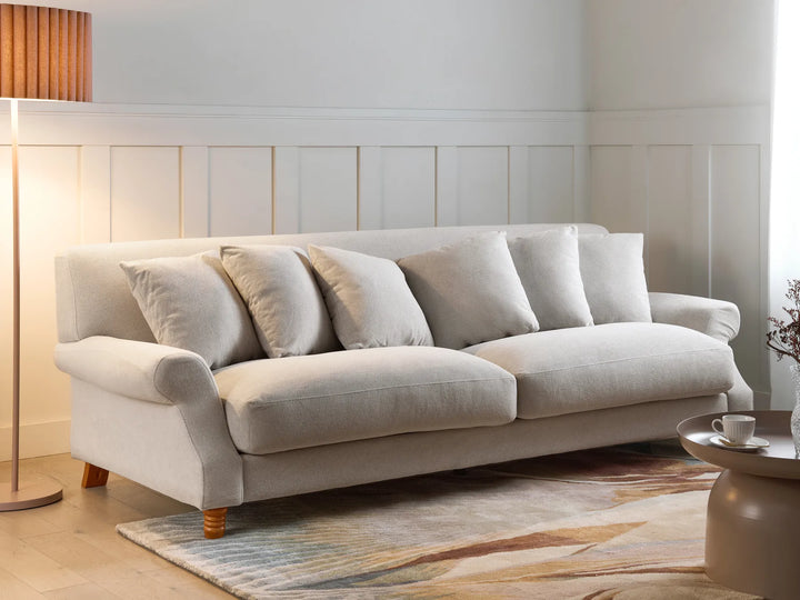 Beige sofa in a living room setting with a lamp and coffee table.