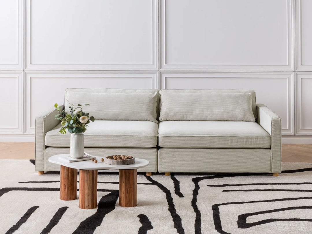 Beige sectional sofa in a living room with a coffee table and decorative items.