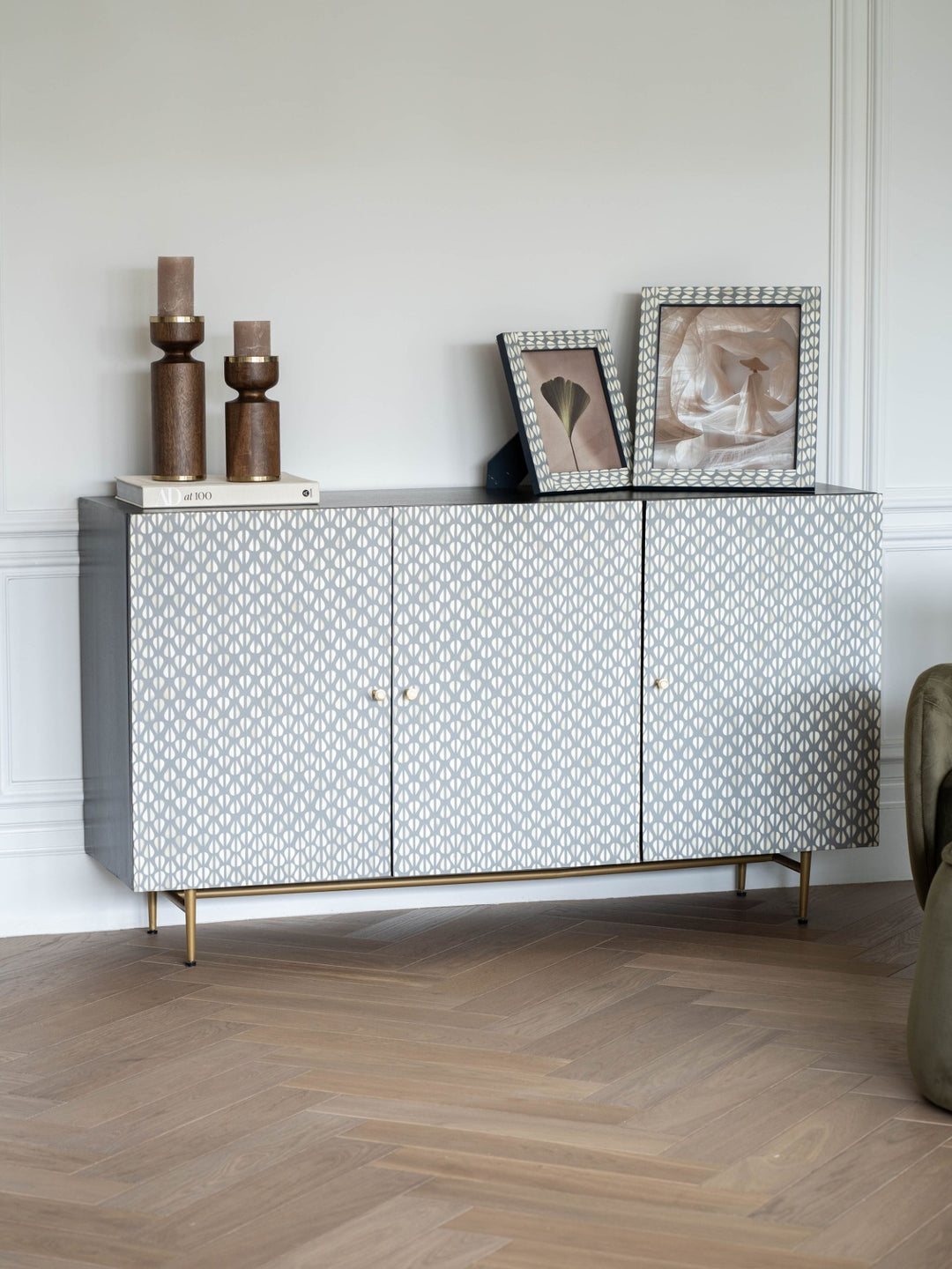 Decorative sideboard with patterned doors in a room with a wooden floor and white walls.