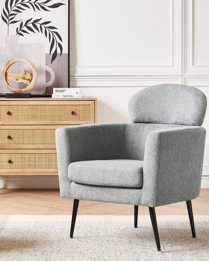Gray armchair in a room with a wooden dresser and decorative items.