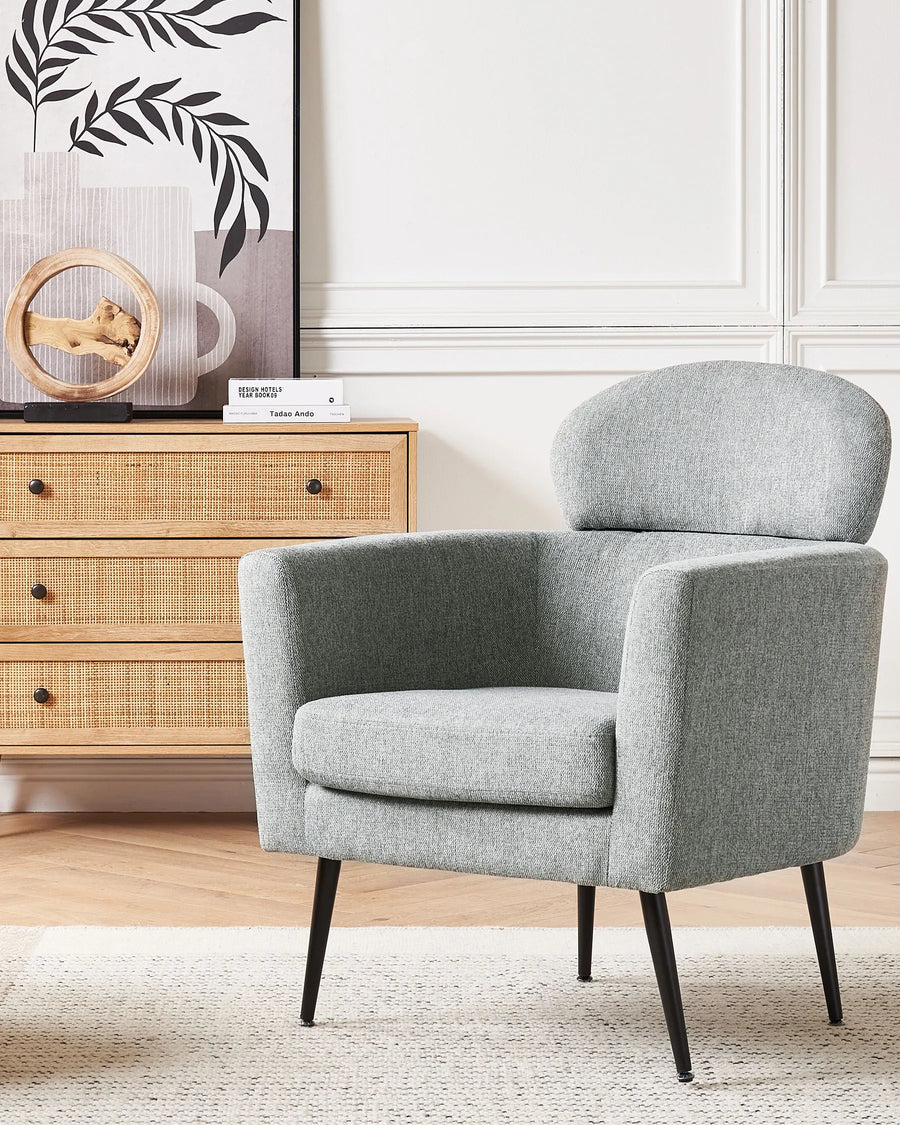 Gray armchair in a room with a wooden dresser and decorative items.