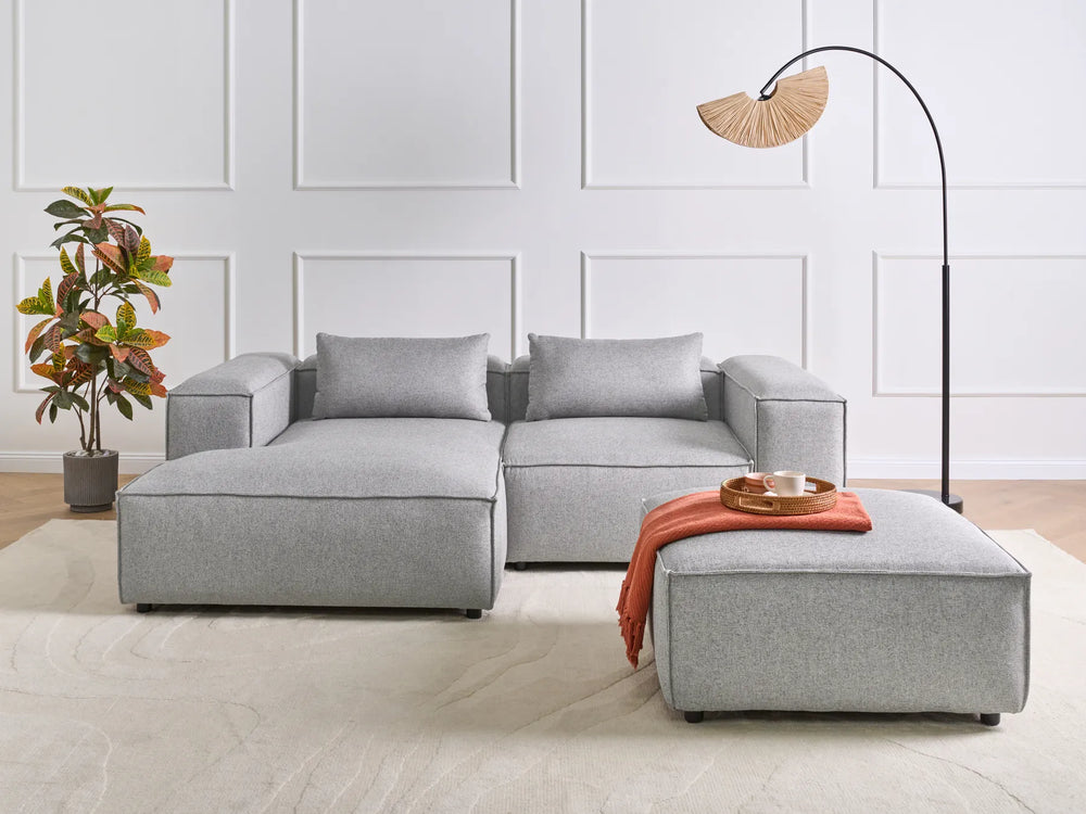 Gray sectional sofa with a matching ottoman in a modern living room setting.