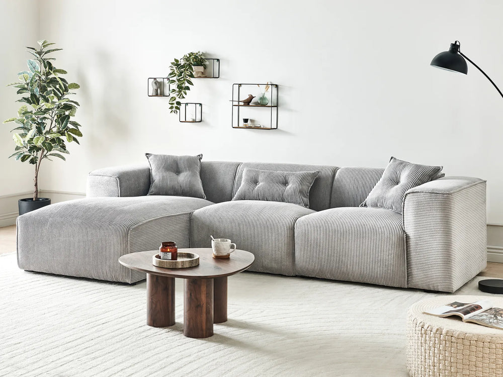Modern living room with a gray sectional sofa, wooden coffee table, and decorative elements.