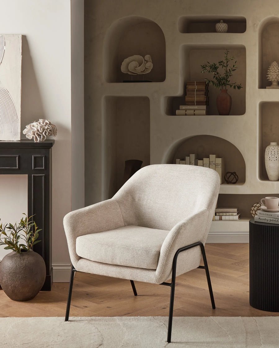 Beige armchair in a stylish living room with shelves and decor.