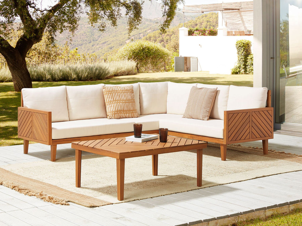Outdoor patio set with wooden furniture and white cushions on a patio.