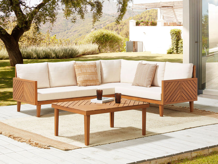 Outdoor patio set with wooden furniture and white cushions on a patio.
