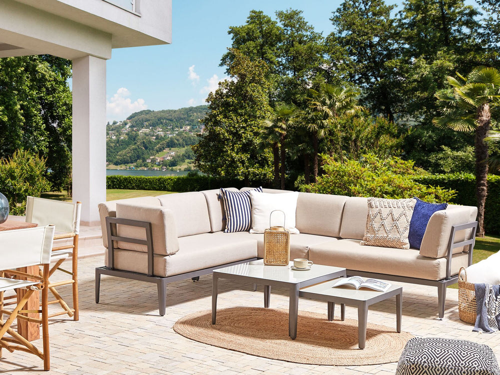 Outdoor patio with beige sectional sofa, coffee table, and chairs with a scenic background.