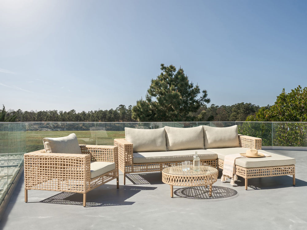 Outdoor patio set with wicker furniture and cushions on a clear day.