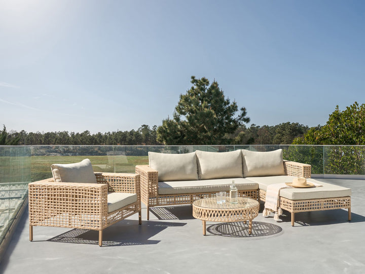 Outdoor patio set with wicker furniture and cushions on a clear day.
