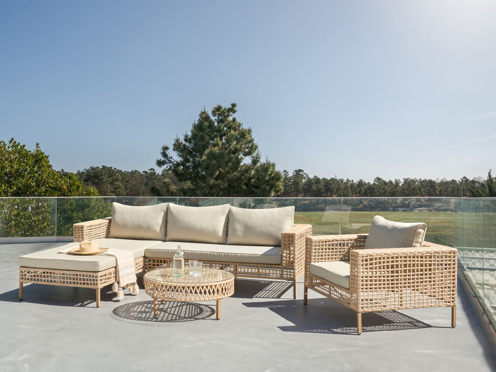 Outdoor patio furniture set with cushions on a rooftop with a clear sky and trees in the background.