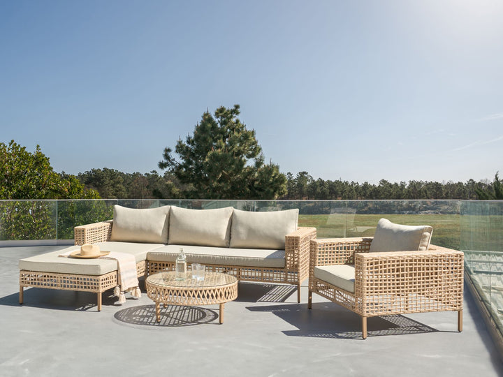 Outdoor patio furniture set with cushions on a rooftop with a clear sky and trees in the background.
