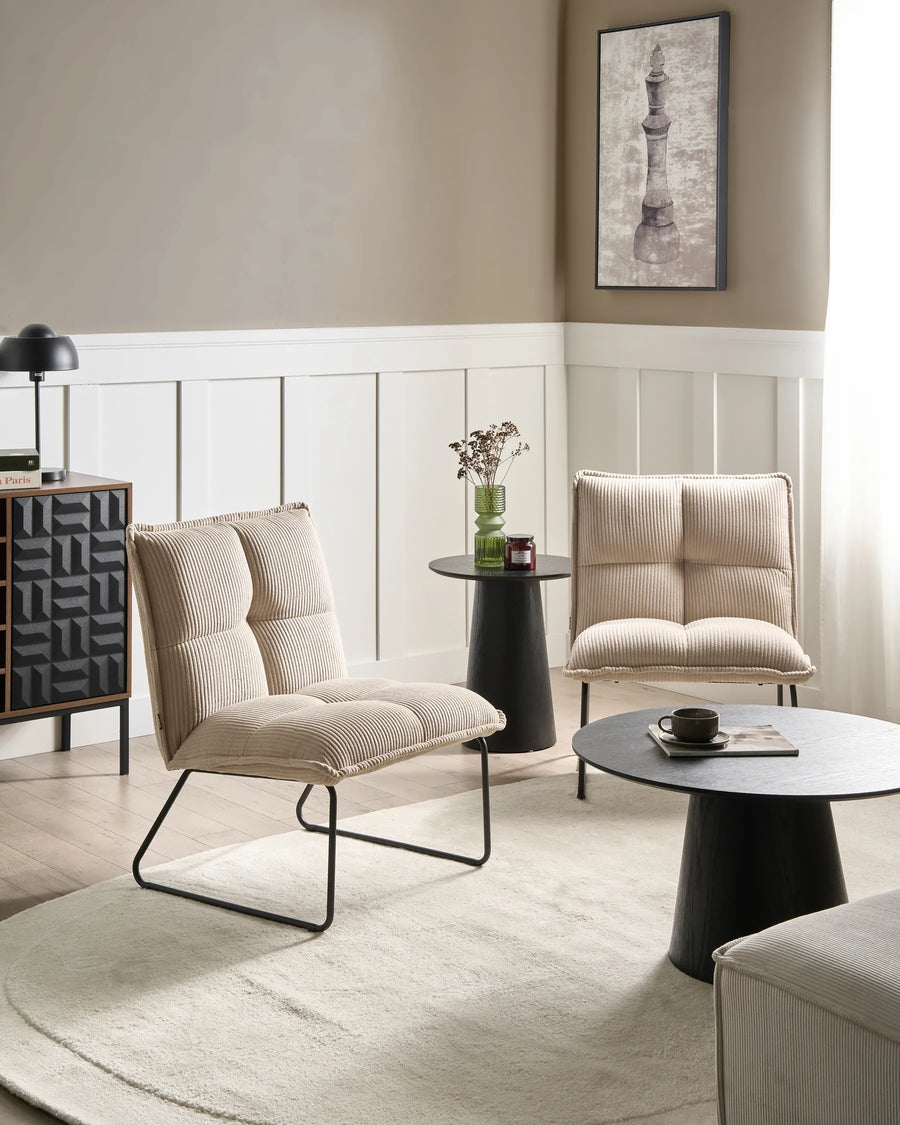 Modern living room with beige armchairs, a round coffee table, and decorative elements.