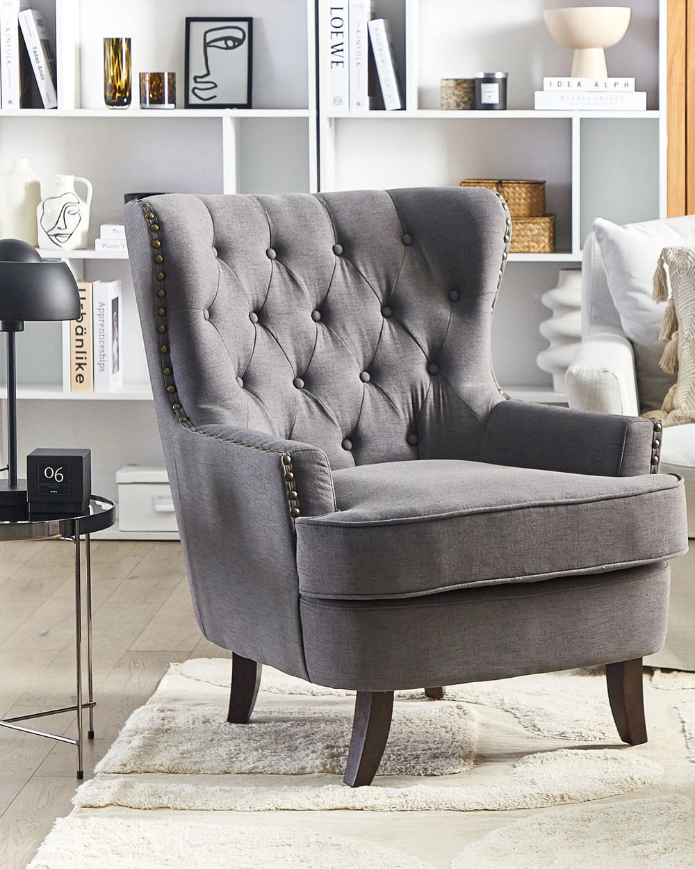 Gray armchair in a living room setting with books and decor on shelves.