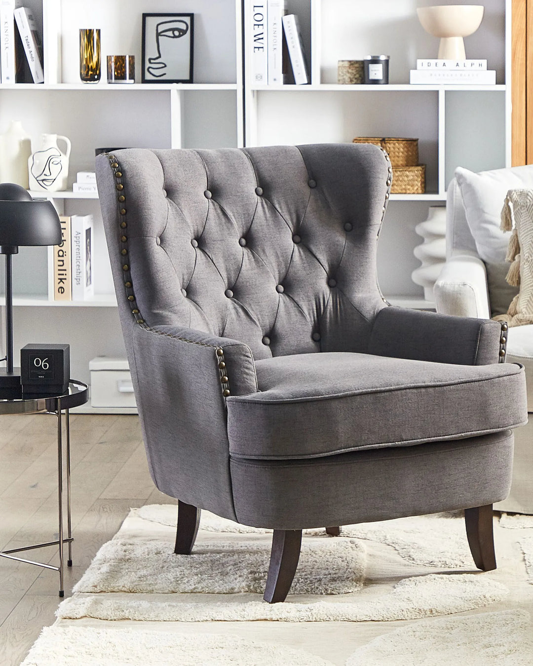 Gray armchair in a living room setting with books and decor on shelves.