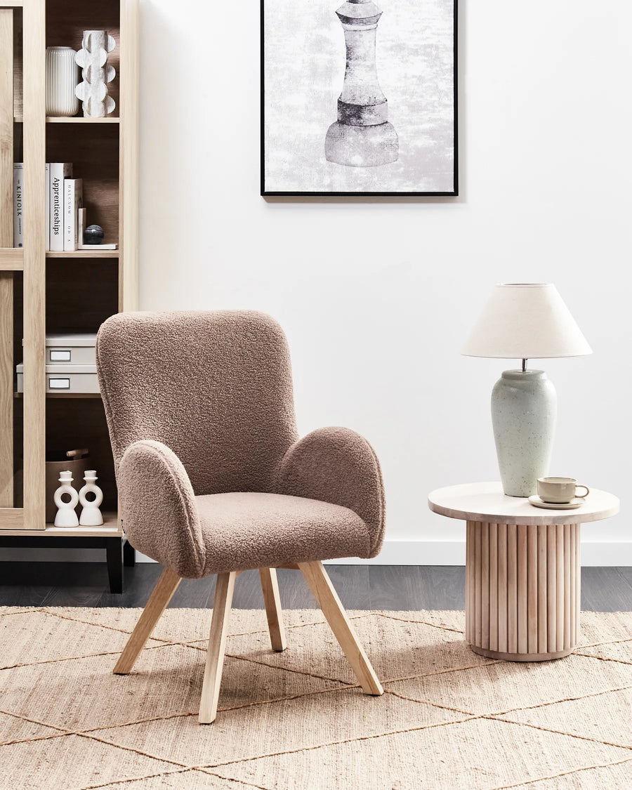 Beige armchair in a modern living room with a side table and lamp.