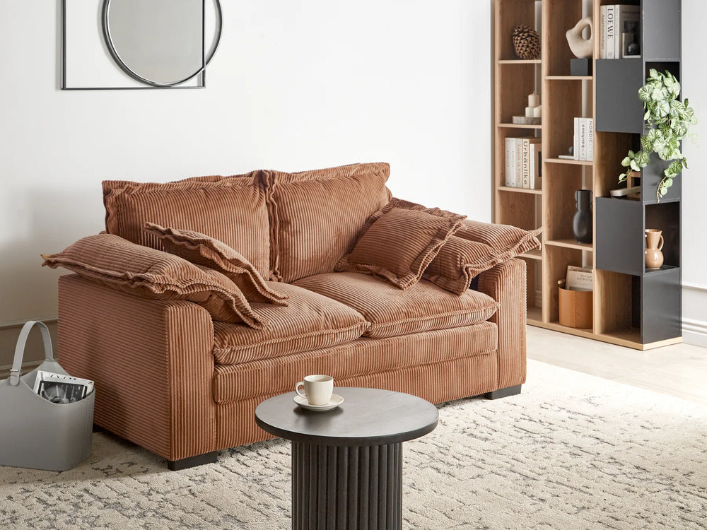 Brown sofa in a living room with a coffee table and bookshelf.