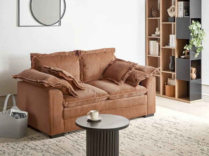 Brown sofa in a living room with a coffee table and bookshelf.