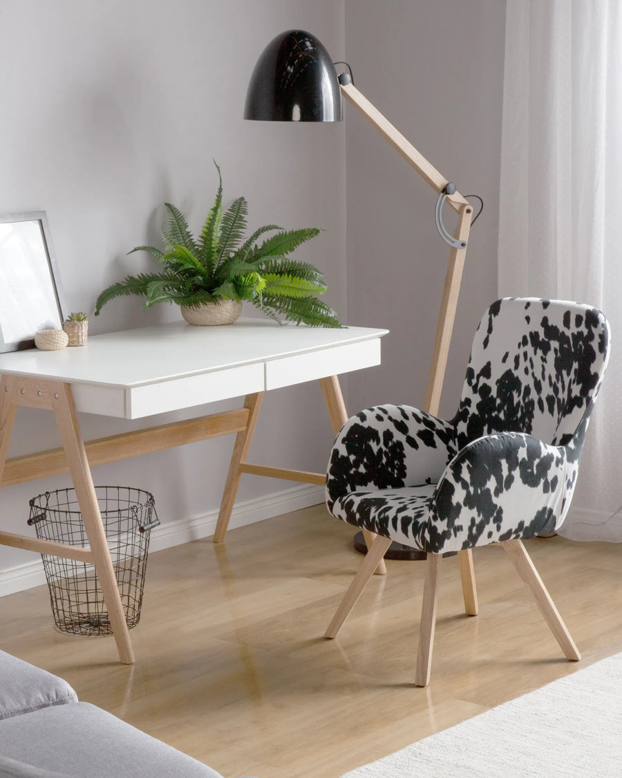 Modern home office with a white desk, black and white patterned chair, and a black lamp.