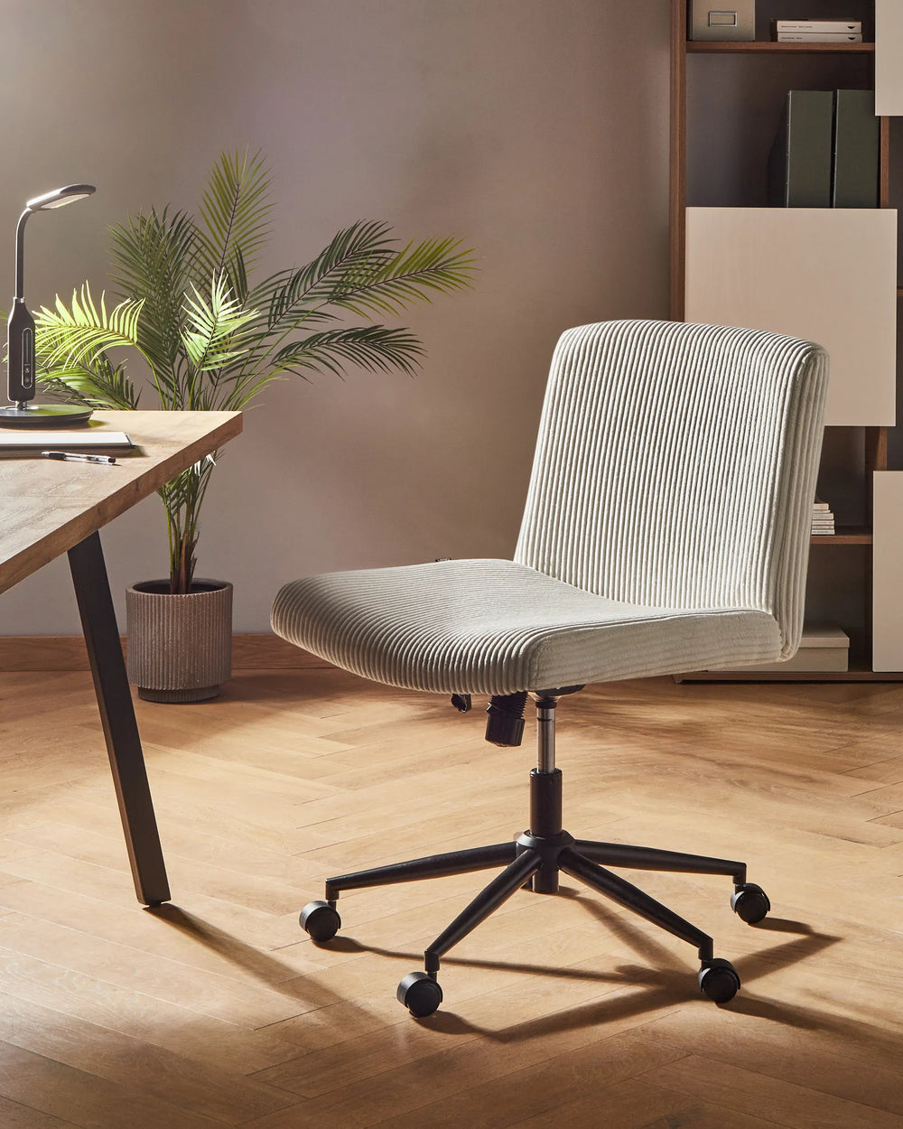 Gray office chair in a home office setting with a desk, plant, and bookshelf.