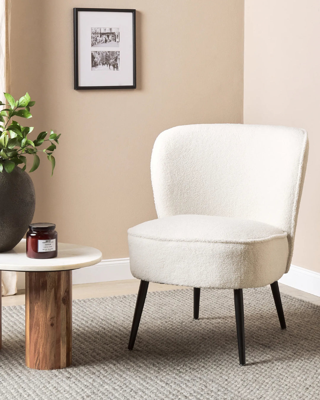 White upholstered chair in a room with a wooden side table and plant