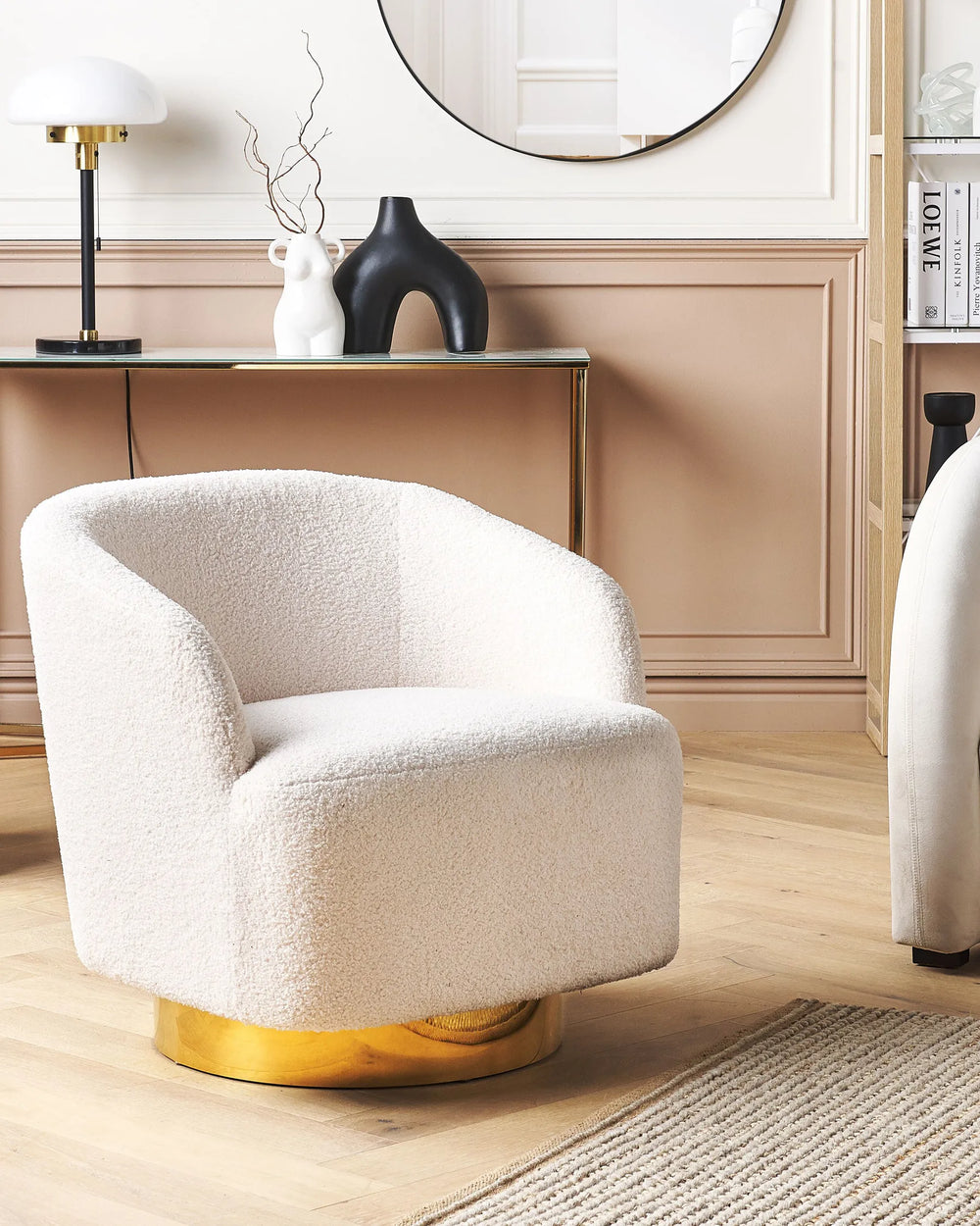 Beige armchair with gold base in a room with a table and decorative items.