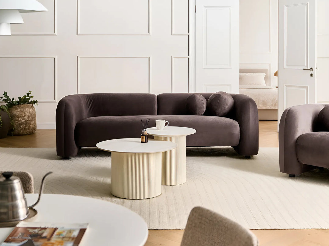 Modern living room with a brown sofa, coffee table, and decorative items.