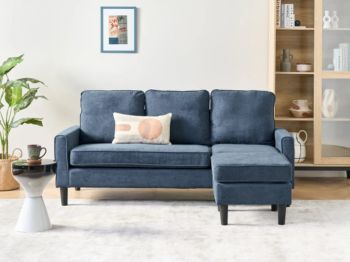 Blue sectional sofa in a living room setting with a plant and coffee table.