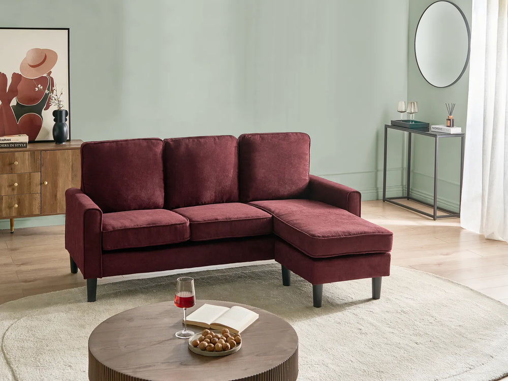 Maroon sectional sofa in a living room setting with a coffee table and decor items.