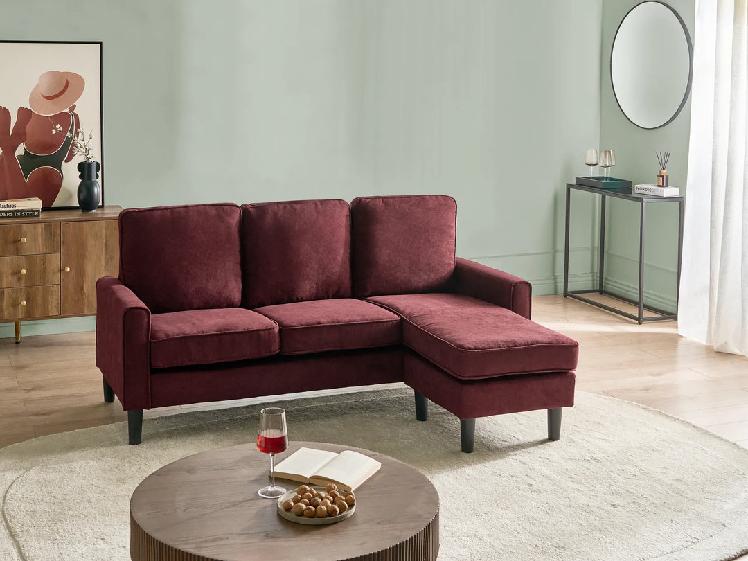 Maroon sectional sofa in a living room setting with a coffee table and decor items.