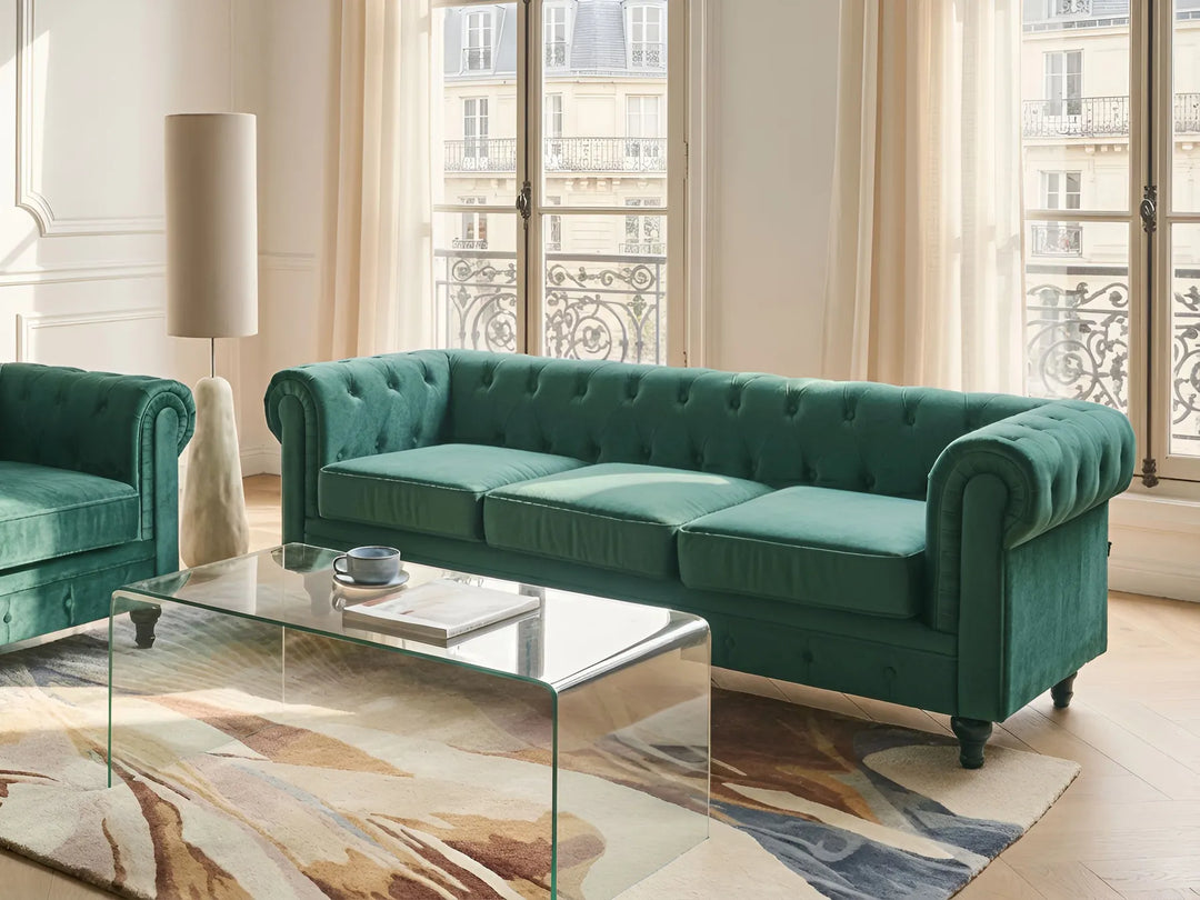 Green velvet sofa in a stylish living room with large windows.