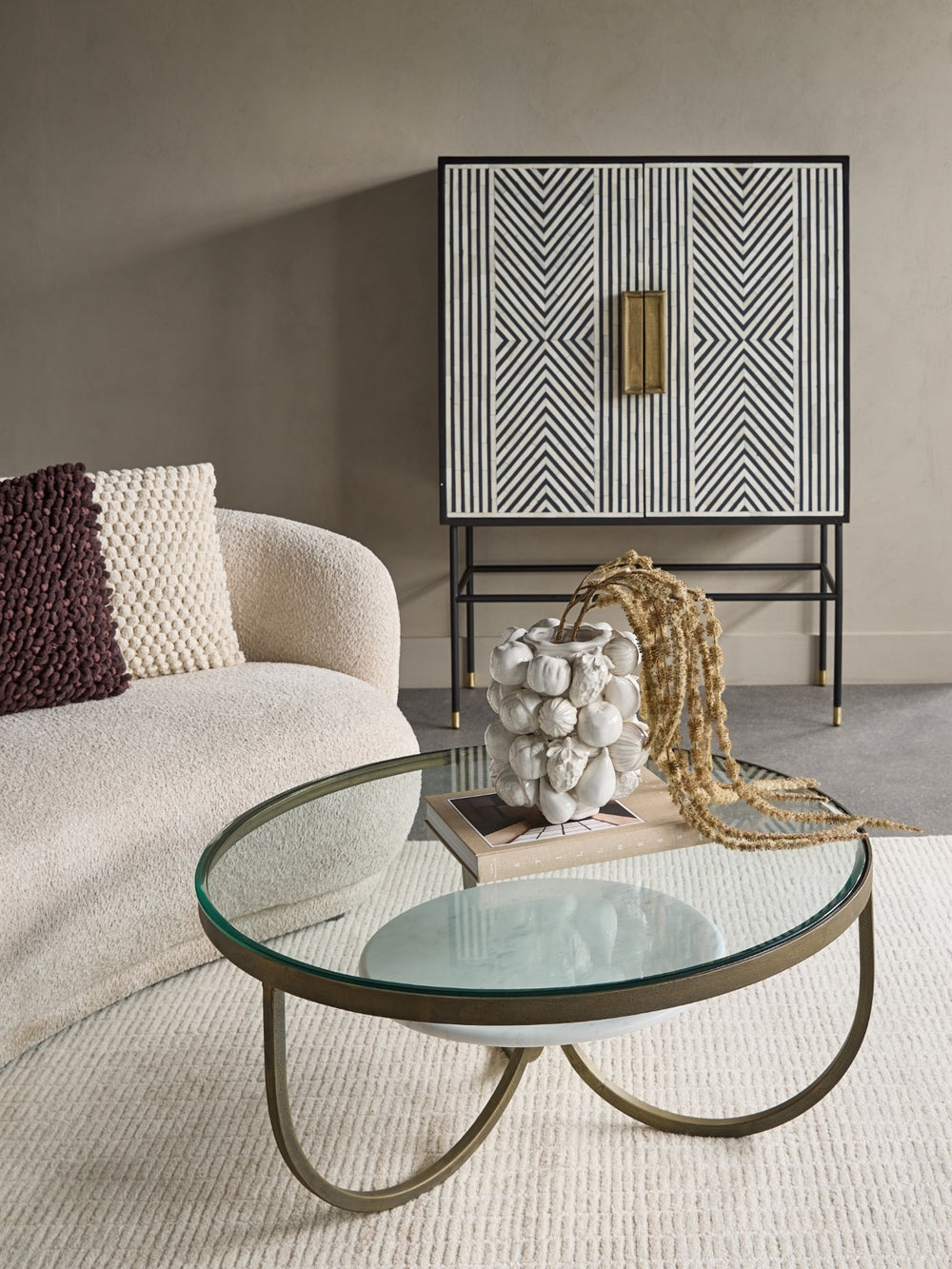 Modern living room with a glass coffee table, patterned cabinet, and textured sofa.