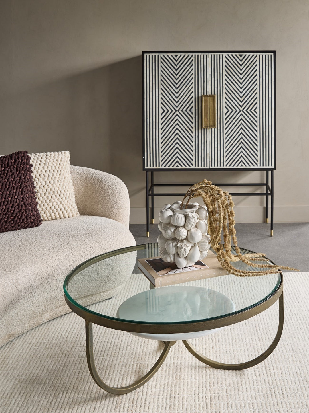 Modern living room with a glass coffee table, patterned cabinet, and textured sofa.