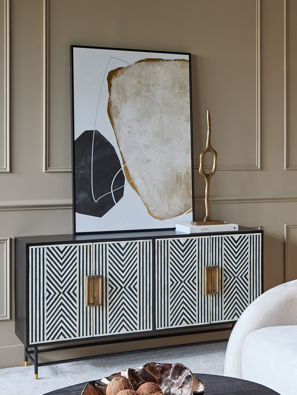 Modern interior with a black and white patterned cabinet, abstract art, and decorative sculpture.