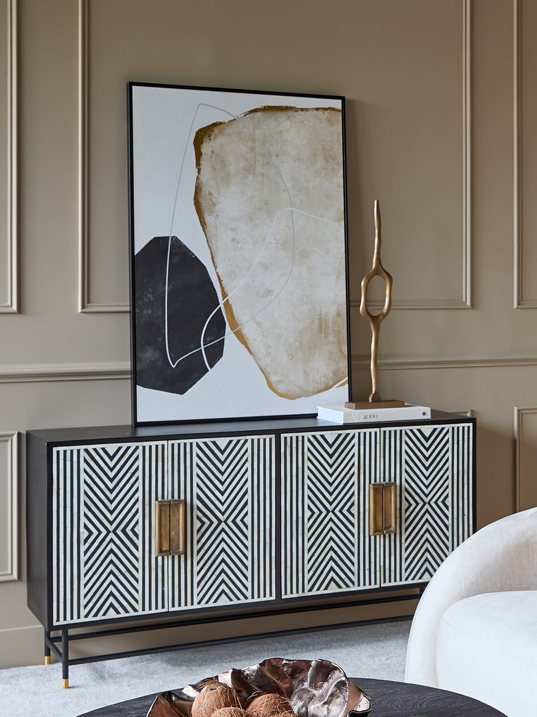 Modern interior with a black and white patterned cabinet, abstract art, and decorative sculpture.