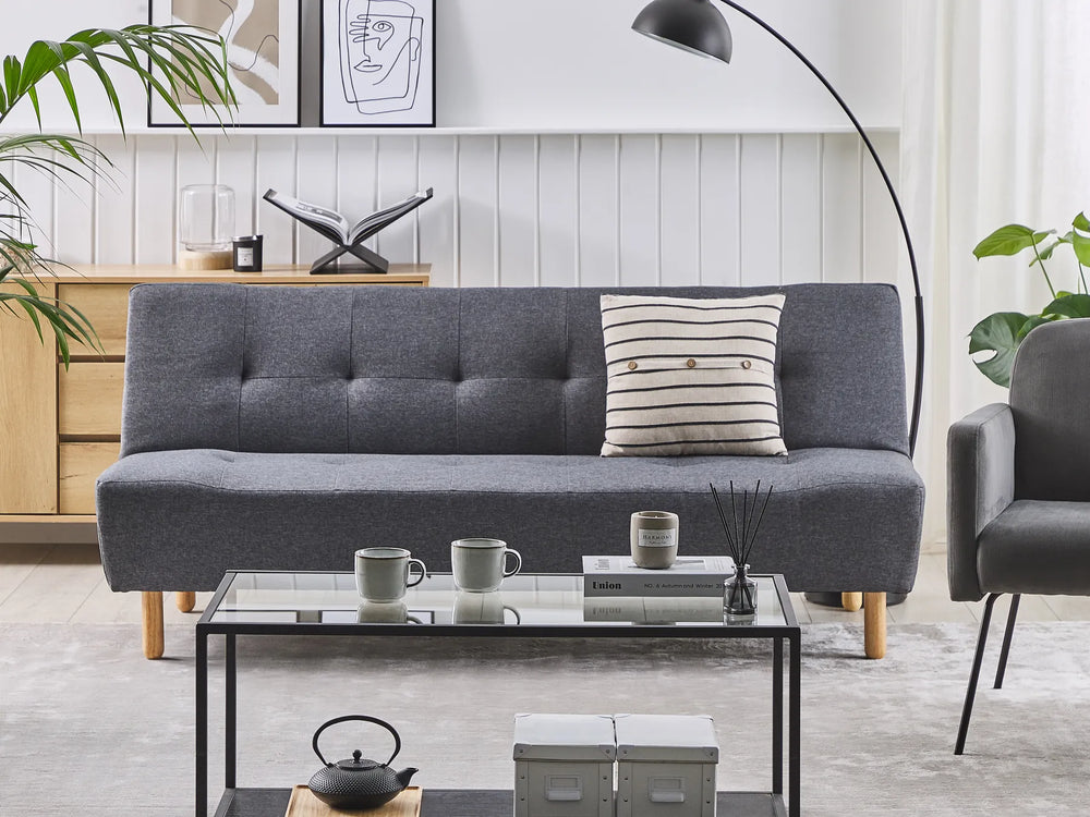 Gray sofa with a pillow in a living room setting with a coffee table and decor items.