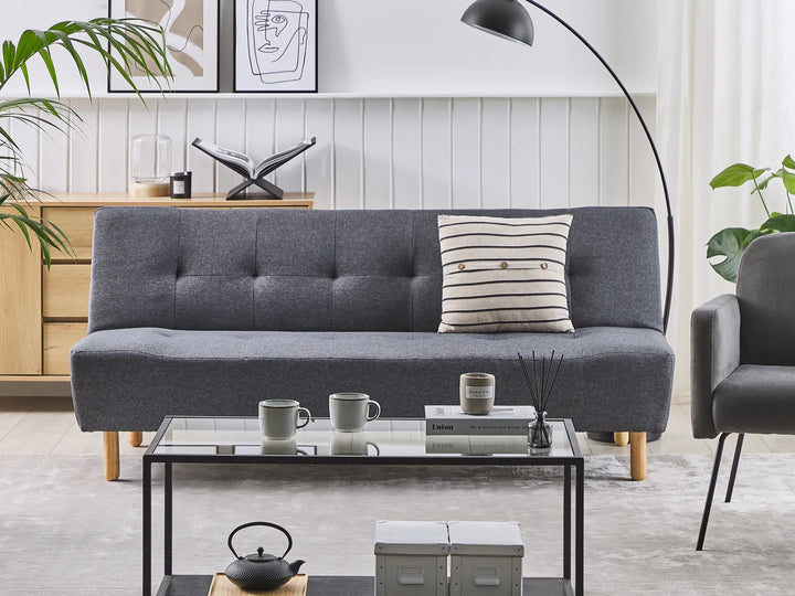 Gray sofa with a pillow in a living room setting with a coffee table and decor items.