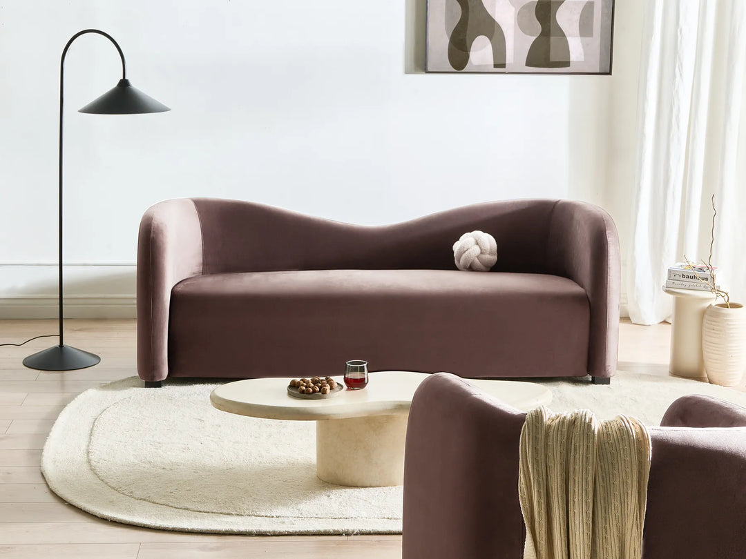 Modern living room with a brown sofa, round coffee table, and abstract art on the wall.