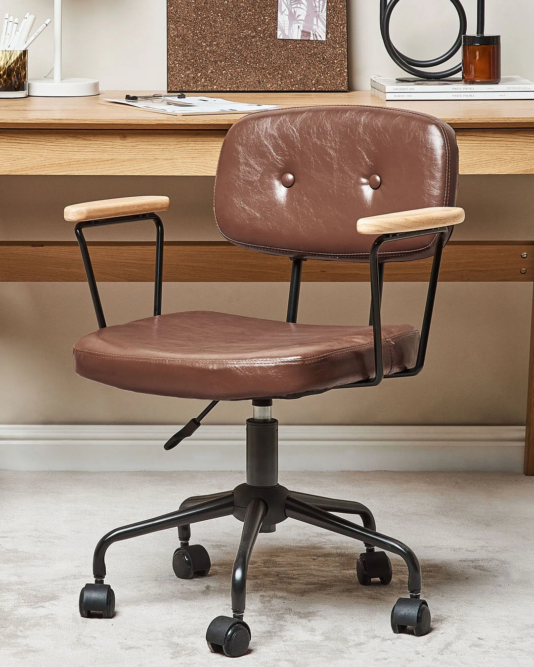 Brown office chair with black metal base in front of a wooden desk.