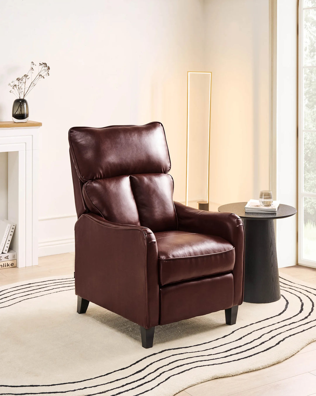 Brown leather recliner chair in a living room setting with a side table and decor.