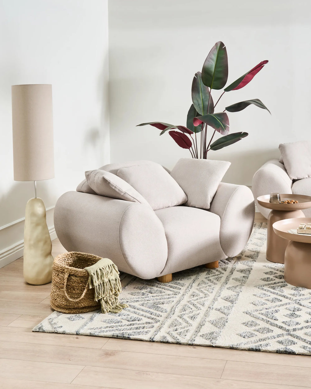 Modern living room with a beige armchair, lamp, and decorative items.