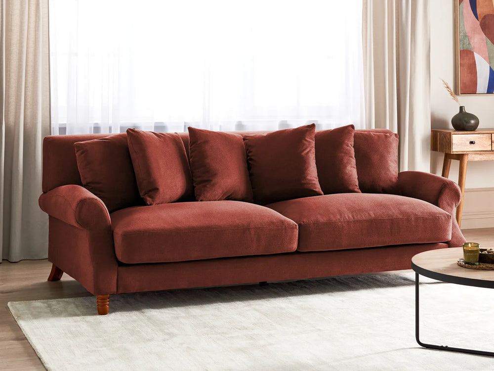 Red sofa in a living room setting with a coffee table and decorative items.